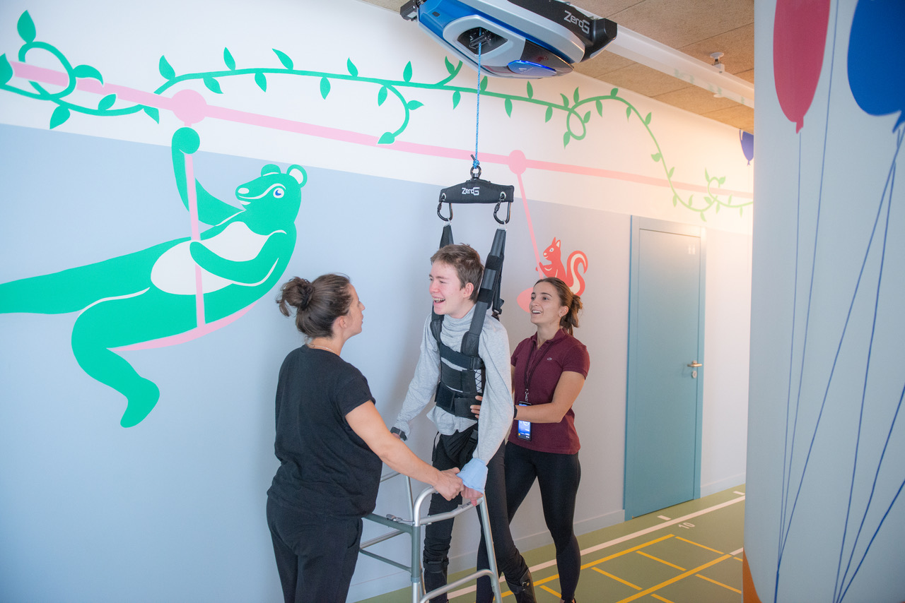 deux physiothérapeutes aident un enfant à se déplacer avec le rail zeroG® au centre qap